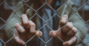 hands grasping fence
