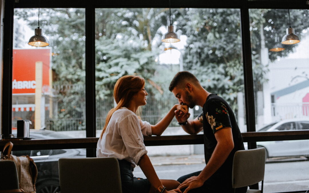 couple at a restaurant; he is kissing her hand